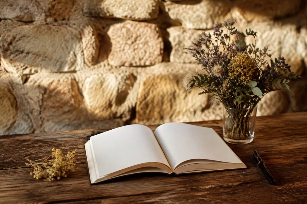 Carnet de souvenirs ouvert avec stylo-plume et fleurs séchées sur une table en bois