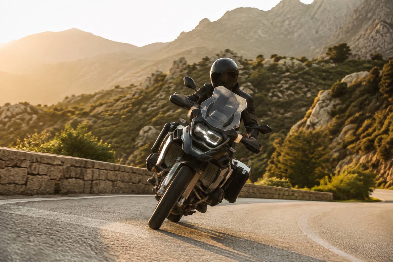 Moto d'aventure penchée dans un virage serré sur route de montagne ensoleillée